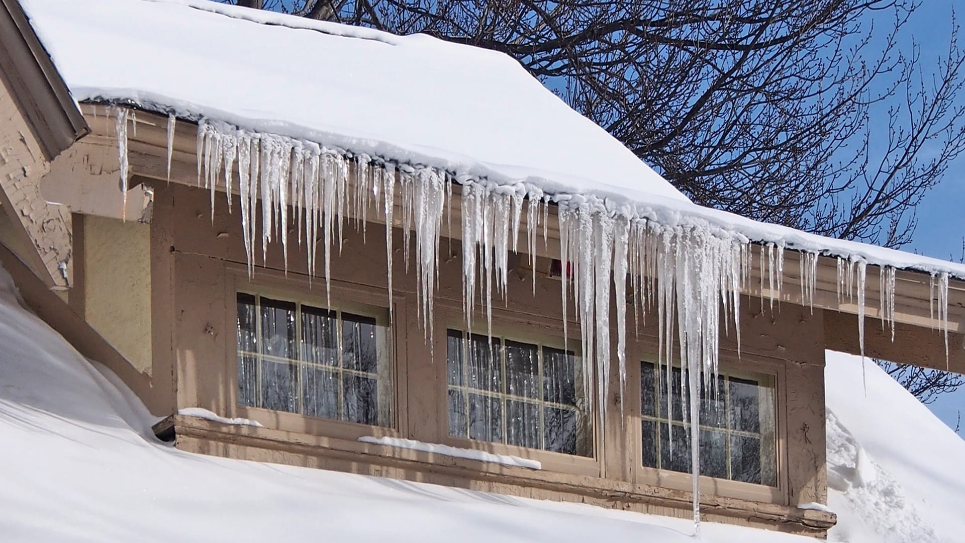 snow covered roof with icicles formed over eave