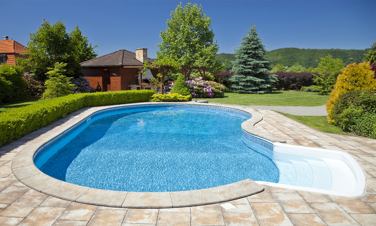 backyard pool next to house with brown shingles