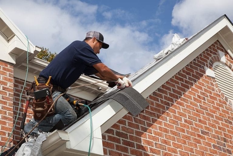 contractor cutting a shingle at a roof's rake edge