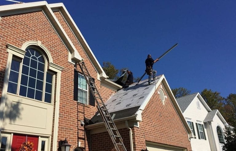 roofers installing underlayment and eave membrane on a roof