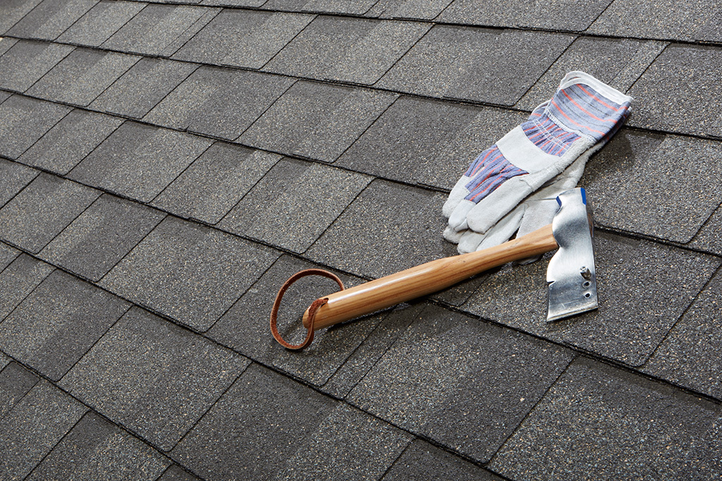 gloves and roofing hatchet on asphalt shingles