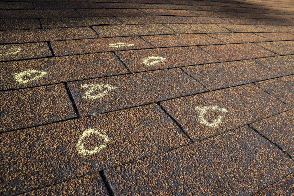 damage caused to roof shingles from hail marked on roof