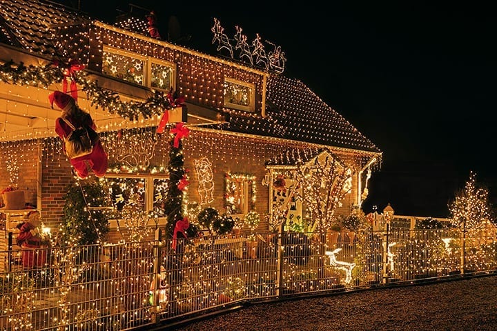 house with Xmas lights attached to the perimeter fence, the roof's surface and windows