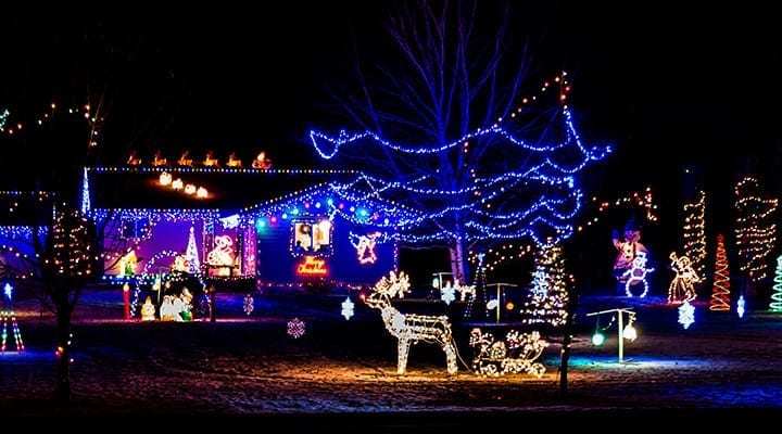 house outlined with Xmas lights + lighting on trees and other Xmas props