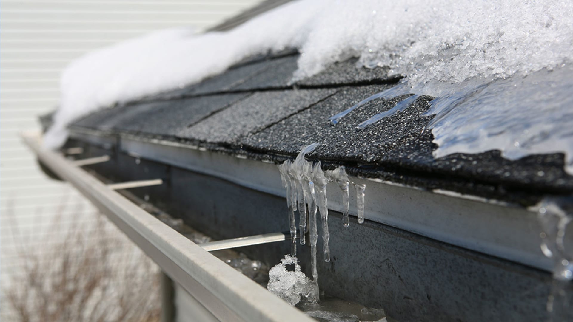 close view of roof eave and gutter with ice and snow