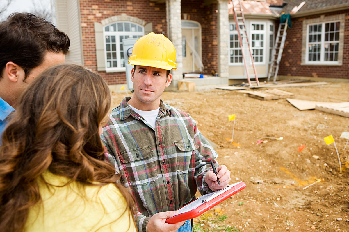 contractor meeting couple in front of home under construction