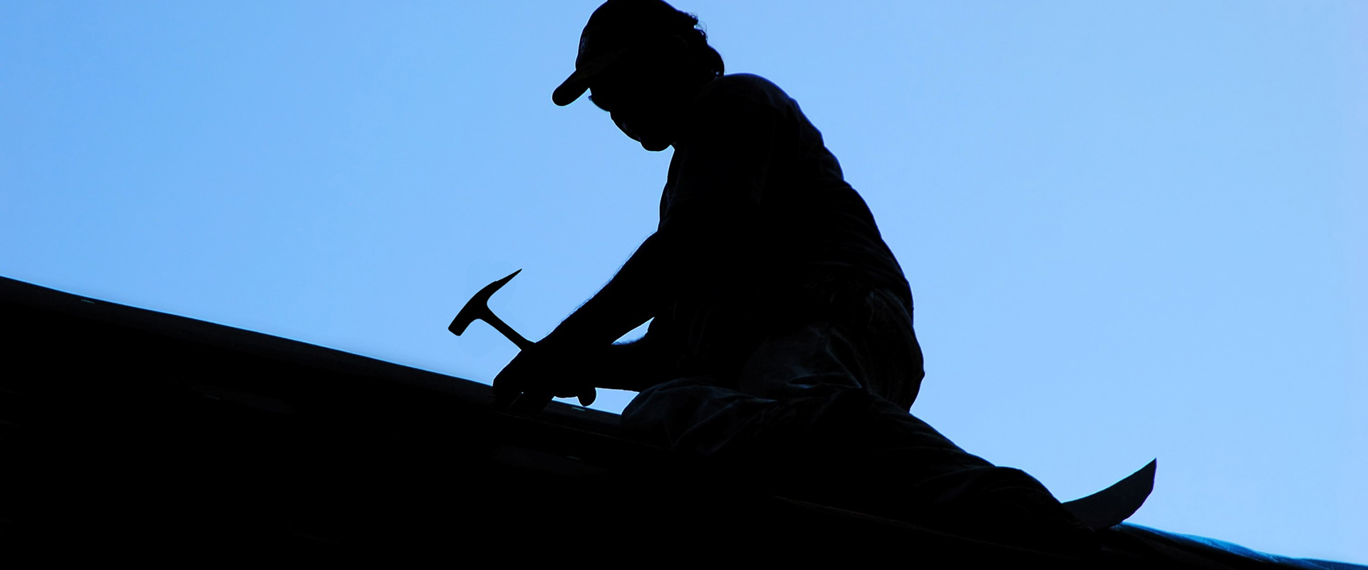 sillouette of roofer holding roofing-hammer
