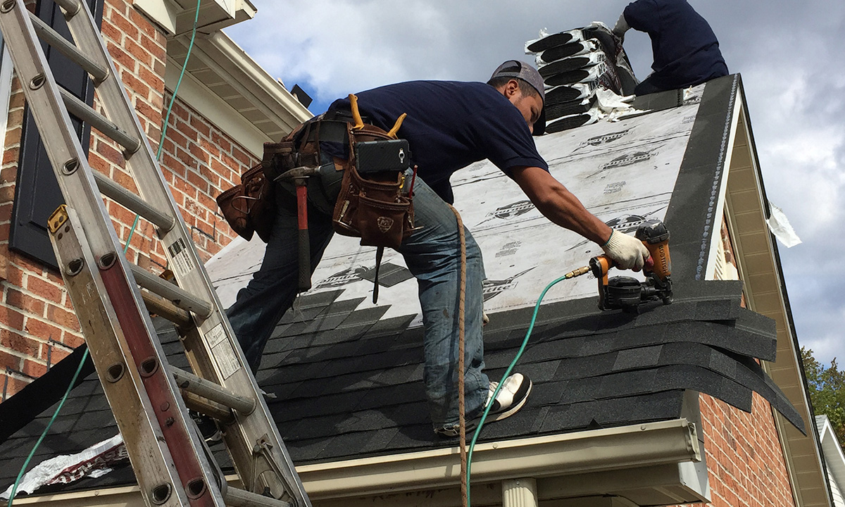 roofer on a roof holding a nail gun