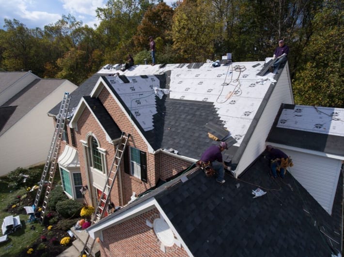 Roofers applying underlayment and shingles