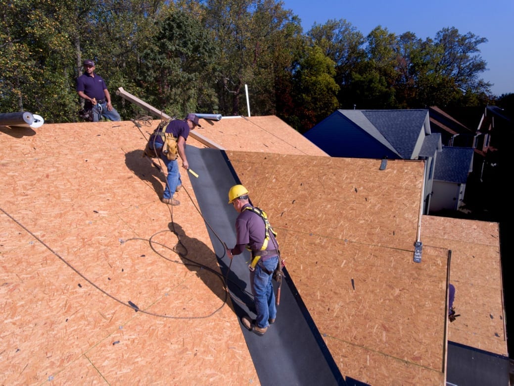 Roofers applying underlayment in a roof valley