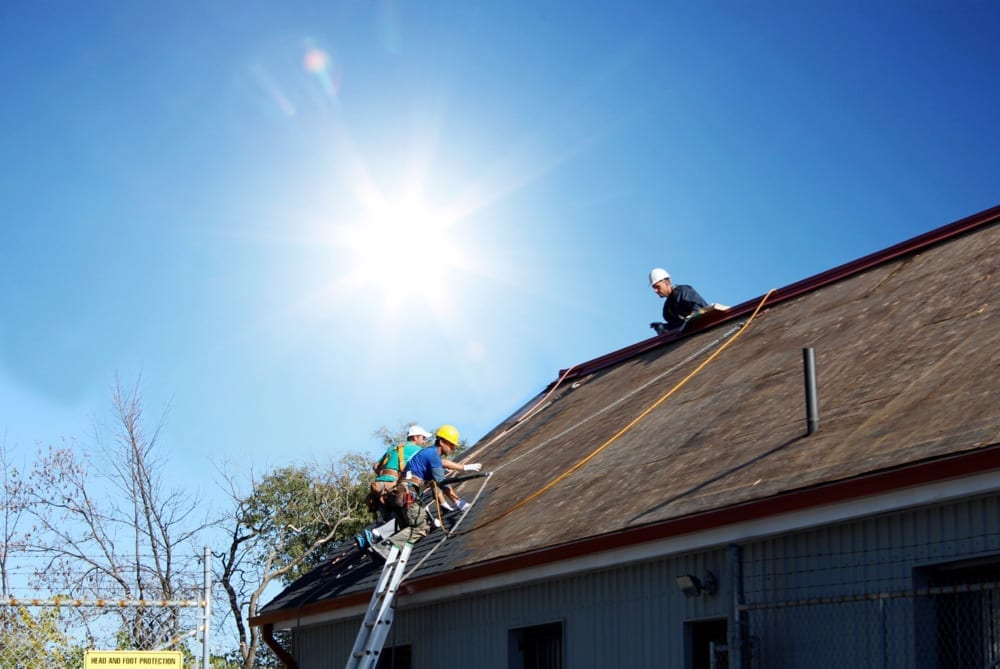 Roofers working on top of roof in summer heat